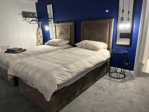 1 dormitorio con 1 cama grande y pared azul en Beautiful 2-Bed House in Bridgend en Bridgend