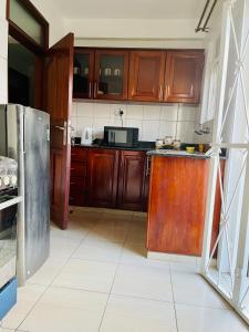 uma cozinha com armários de madeira e um frigorífico de aço inoxidável em Khael Glory home offers 247 security em Kampala