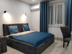 1 dormitorio con cama con sábanas azules y silla en Lux na Druhetiv, en Uzhhorod