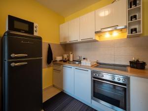 a kitchen with a black refrigerator and white cabinets at Green Apple Apartment in Subotica