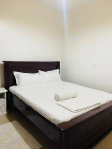 uma cama com uma estrutura de madeira e lençóis brancos em Khael Glory home offers 247 security em Kampala