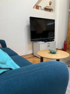 a living room with a tv and a blue couch and a table at Apartman 55 in Kikinda