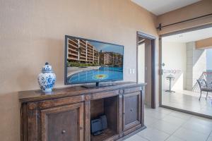 a flat screen tv sitting on top of a wooden entertainment center at Sonoran Sun 2BR SE 703 by Casago in Puerto Peñasco