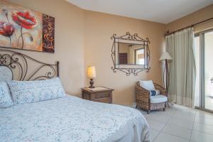 een slaapkamer met een bed, een spiegel en een stoel bij Sonoran Sun 2BR SE 703 by Casago in Puerto Peñasco