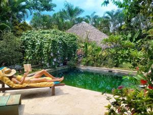 uma mulher deitada numa cadeira ao lado de uma piscina em Dream Glamping Jungle Bohio em Las Terrenas