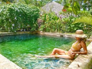 una mujer con sombrero sentada en una piscina en Dream Glamping Jungle Bohio en Las Terrenas