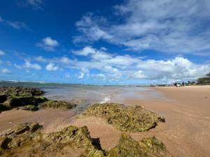 una playa con rocas en la arena y el océano en Guarajuba, Duplex pé na areia. Ótima localização!, en Guarajuba