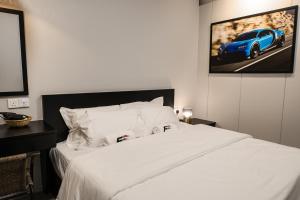 Tanjong Tokong的住宿－FAST FIVE At Gurney，卧室配有白色床,墙上挂着一辆蓝色汽车