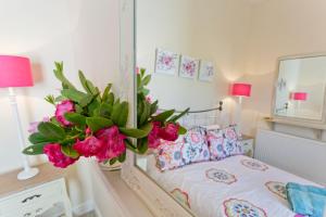 a bedroom with a bed with a mirror and pink flowers at Penlon in Rhosneigr