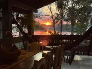 a porch with a hammock with a sunset in the background at Casa do Lago Hospedaria in Brasilia