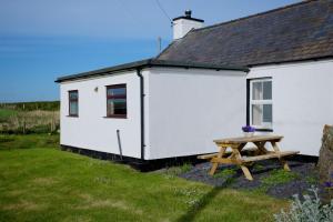 a white cottage with a picnic table in front of it at Penlon in Rhosneigr