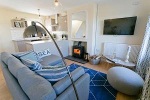 a living room with a blue couch and a kitchen at Penrhyn Gwyn in Aberffraw