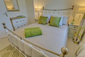 a bedroom with a white bed with green pillows at Penrhyn Gwyn in Aberffraw