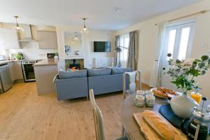 a kitchen and living room with a couch and a table at Penrhyn Gwyn in Aberffraw