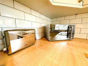a kitchen with stainless steel appliances and a wooden floor at Cute Country Cottage near Leeds & York in Leeds