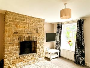 a living room with a stone fireplace with a television at Cute Country Cottage near Leeds & York in Leeds