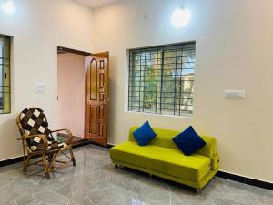 ein Wohnzimmer mit einer grünen Couch und einem Stuhl in der Unterkunft Pal's Cottage in Mysore