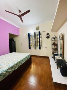 a bedroom with a bed and a ceiling fan at Pal's Cottage in Mysore