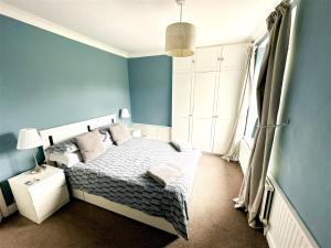 a bedroom with a bed and a blue wall at Cute Country Cottage near Leeds & York in Leeds