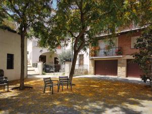 two chairs under a tree in front of a building at BlauMasnou One step to the beach! in El Masnou