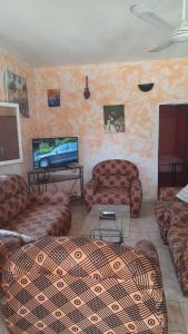 uma sala de estar com sofás e uma televisão de ecrã plano em Chez Andre em Ngaparou