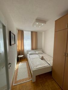 um pequeno quarto com uma cama e um armário em Dženx Apartmani em Sarajevo