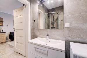 Allure Nautica Aparthotel في شتتين: حمام أبيض مع حوض ومرآة