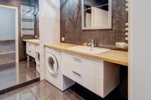 a bathroom with a sink and a washing machine at Allure Nautica Aparthotel in Szczecin
