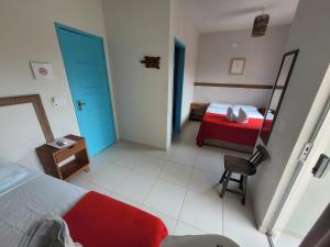 a bedroom with a red bed and a blue door at Pousada Tartaruga in Maragogi