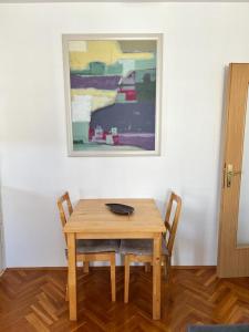 einen Holztisch mit zwei Stühlen und ein Gemälde an der Wand in der Unterkunft Apartment Sunny day in Livno