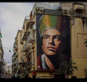 Una gran pintura de un hombre al lado de un edificio en La dimora delle zite, en Nápoles