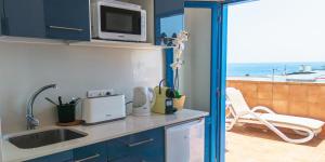 a kitchen with a sink and a microwave and a balcony at Hostal Magec in Puerto del Carmen