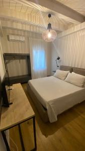 Un dormitorio con una gran cama blanca y una lámpara de araña. en I giardini del borgo, en Vico nel Lazio