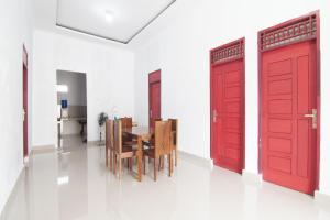 a dining room with red doors and a table at OYO 93088 Celine Home Syariah in Parit