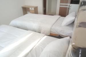 2 camas en una habitación de hotel con sábanas blancas en OYO 93088 Celine Home Syariah, en Parit