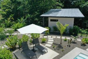 um guarda-sol branco e duas cadeiras e uma casa em Sharma Costa Rica - Heliconia Casita em Uvita