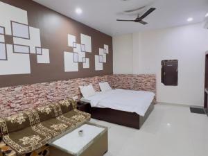 a bedroom with a bed and a couch and a tv at ALOK RESIDENCY in Satna