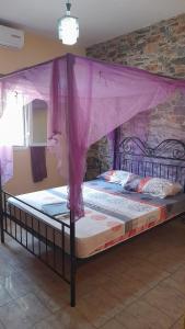 a bed with a purple canopy in a room at Chez Andre in Ngaparou