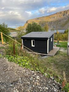 a small black house with a ramp in a field at Overnatting med sjøutsikt å rolige omgivelser in Alta