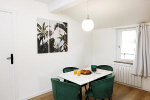uma sala de jantar com uma mesa branca e cadeiras verdes em Le T2 Chic ! em Carcassonne