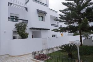 ein weißes Gebäude mit einem Baum davor in der Unterkunft Duplex face la résidence d ambassadeur de l Angleterre in La Marsa