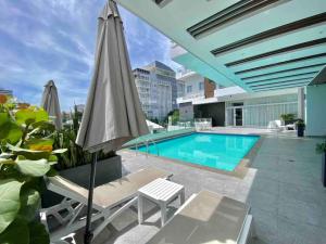 an umbrella and chairs next to a swimming pool at Elegant City Center Condo in Santo Domingo