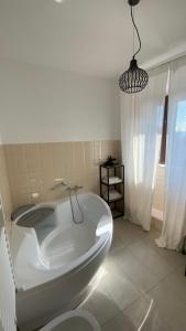 uma banheira branca num quarto com uma janela em I giardini del borgo em Vico nel Lazio