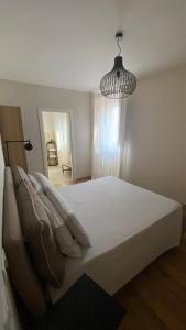 een slaapkamer met een wit bed en een hanglamp bij I giardini del borgo in Vico nel Lazio
