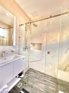 a bathroom with a glass shower and a sink at Stunning City Center Condo in Los Prados