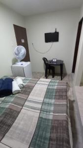 a bedroom with a bed with a fan and a television at Rioli quarto 2 in Caruaru