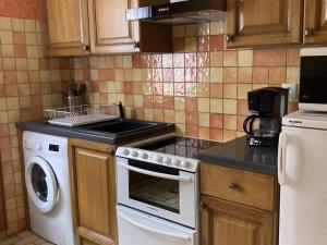 Il comprend une cuisine équipée d'une cuisinière blanche et d'un lave-vaisselle. dans l'établissement Charmant 2 pièces avec parking et Wi-Fi à Saint-Chaffrey - FR-1-762-46, à Saint-Chaffrey