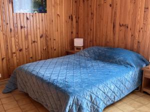 - une chambre avec un lit bleu dans un mur en bois dans l'établissement Charmant 2 pièces avec parking et Wi-Fi à Saint-Chaffrey - FR-1-762-46, à Saint-Chaffrey