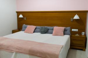 a bedroom with a large bed with pink and blue pillows at Hostal Imperial Merida in Mérida