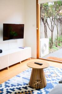 uma sala de estar com uma mesa de centro e uma televisão em Eden-Stay like locals in Fitzroy North em Melbourne